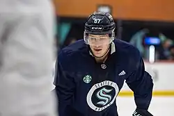 Ice hockey player in a Seattle Kraken jersey and blue helmet
