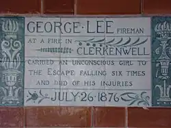 A tablet formed of six standard sized tiles, bordered by green flowers in the style of the Arts and Crafts movement