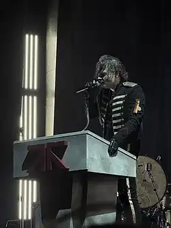 Gerard Way in a skeleton-themed military uniform on a podium delivering the opening words of "Welcome to the Black Parade"
