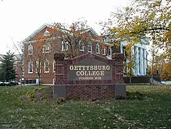 Sign for Gettysburg College with campus buildings in the background