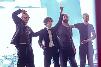 The 1975 as headliners of Glastonbury Festival 2025. From left to right: George Daniel, Matty Healy, Ross MacDonald, and Adam Hann.