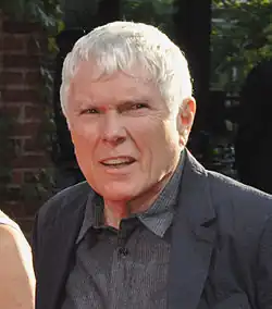 Portrait photograph of Glenn O'Brien, a middle-aged man with light hair wearing a dark shirt and dark jacket