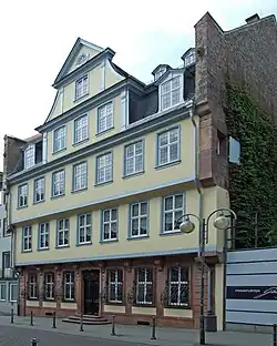 Exterior of the Goethe House on Großer Hirschgraben in Frankfurt am Main, showing its multi-storey yellow facade with gray trim and rows of rectangular windows.