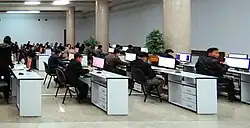A computer lab in which many young adults are working.