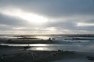 Sandy beach with sunbeams peeking through overcast sky