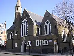 The former St Barnabas Church, Kentish Town Road, Camden in London, 1884–85 by Ewan Christian, now the Greek Orthodox Cathedral of St Andrew, showing the west front with north apse and turret[163]