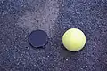 A ground golf ball with a 52&nbsp;mm camera lens cover for comparison