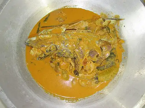 A plate of gulai kepala ikan (fish head's gulai) accompanied by ruku-ruku, slices of blimbi wuluh (Averrhoa bilimbi) and green cabai rawit (bird's eye chilies).