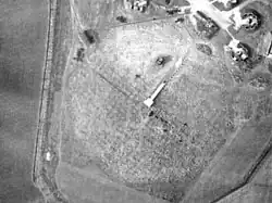 Image of a radar emplacement as seen from the air, in the center of a large mat formed of metal wire.