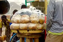 Plastic wrapped gurasa presented on a stool at a local stand