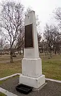 White gravestone with metal sign in cemetery