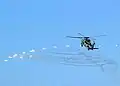 An SH-60B deploys its flares while evasively maneuvering