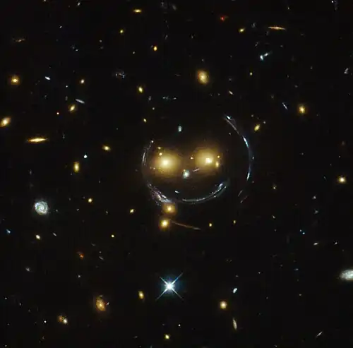 "Smiley" image – galaxy cluster (SDSS J1038+4849) & gravitational lensing (an Einstein ring) (HST).[32]