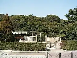 Torii gate and trees behind a stone fence.