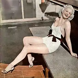 Color photo of Harlow in a swim suit sitting beside a pool