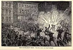 A large crowd of people is in an open area with multi-story buildings in the background. An explosion is happening in the midst of the crowd. The image says, "The Haymarket Riot. The explosion and the conflict."