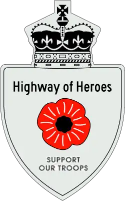 A Highway of Heroes reassurance marker with a red poppy flower in place of a number. Above that is the text Highway of Heroes, and below it SUPPORT OUR TROOPS.