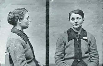 Police mugshots in black and white of middle-aged woman sitting on a chair wearing a cardigan and looking listlessly into the camera