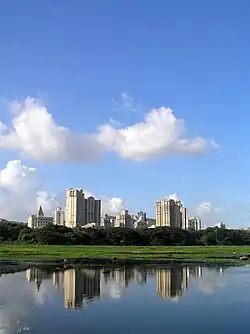 Several multistory residential and commercial buildings overlooking a water body, taken against the backdrop of a clear blue sky with a few cirrus clouds