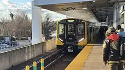 A yellow and black subway train, with stainless steel sides pulling into a station. The train has an MDOT MTA logo in the middle of the front.