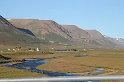 River snaking through flat plane, with mountains and a small town in background.