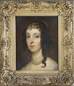 A lady with brown eyes and hair wearing a pearl necklace