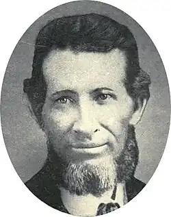 photograph portrait of a man with dark hair and a grizzled chinstrap beard