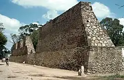 Photograph of the remains of the great walls of Huexotla, towering above the people walking beside them.