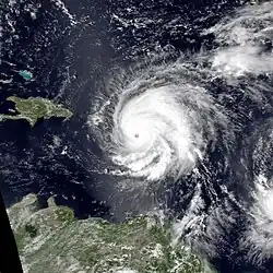 A satellite image of Hurricane Hugo over the Caribbean Sea. The eye is visible and surrounded by dense clouds, with nearby landmasses visible.