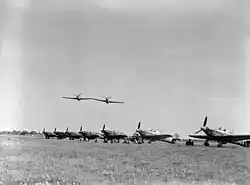 A photograph taken in 1942, of two Hawker Hurricane Mark IIs of No. 43 Squadron RAF, making a low level pass over the other aircraft of the Squadron that are lined up on the ground at RAF Tangmere, Sussex