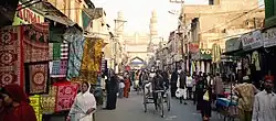 A very busy colorful street with many people walking along rows of little shops