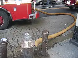 A New York City hydrant hooked to an FDNY fire engine with a fire hose actively pumping water