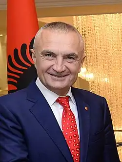 Head shot of Meta smiling with an Albanian flag in the background