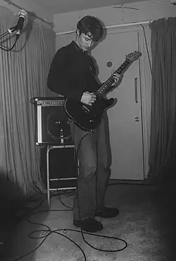 Isaac Wood performing at a Manchester venue in 2020, he holds the guitar and is looking down as he plays.