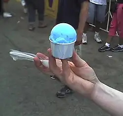 Photo of a person's hand holding a cup of blue-colored Italian ice dessert