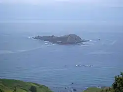 A small rocky island. A sail yacht can be seen behind it for size comparison.