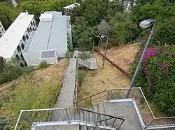 A downwards view of a long stairway down the side of a hill