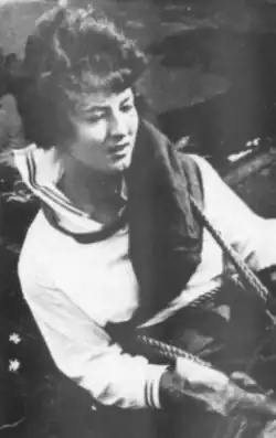 A young white woman with dark hair; a rope is around her torso, because she is rappelling down the face of a dam in Puerto Rico