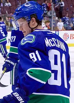 Ice hockey player in a Vancouver Canucks jersey with the number 91 looking downwards