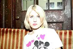Jasmin Baumgartner sitting on a striped sofa, looking directly into the camera