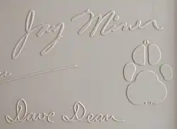 Jay Miner's signature from the top cover of a Commodore Amiga 1000 computer, along with his dog Mitchy's pawprint.