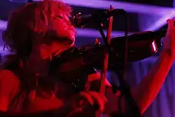 A person plays violin. They're lit with red light.
