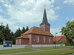 Red brick church with three windows and steeple