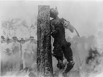 A burned corpse hanging from a tree