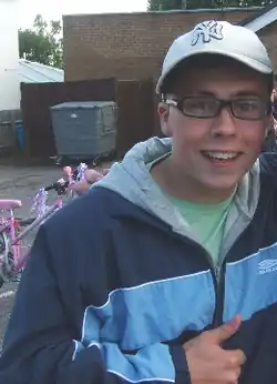A man with a white hat and glasses, smiling at the camera.