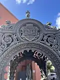 Close of the crest on the fountain. It reads Haud Pluribus Impar.
