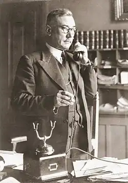 A photograph of Josef Hoop standing while on the telephone in 1945.