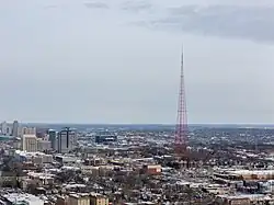 Red TV tower with downtown Kansas City, Missouri in the background, as seen from a drone.