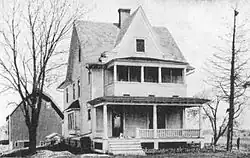 late-19th-century two-story farmhouse with porches and a barn in the background