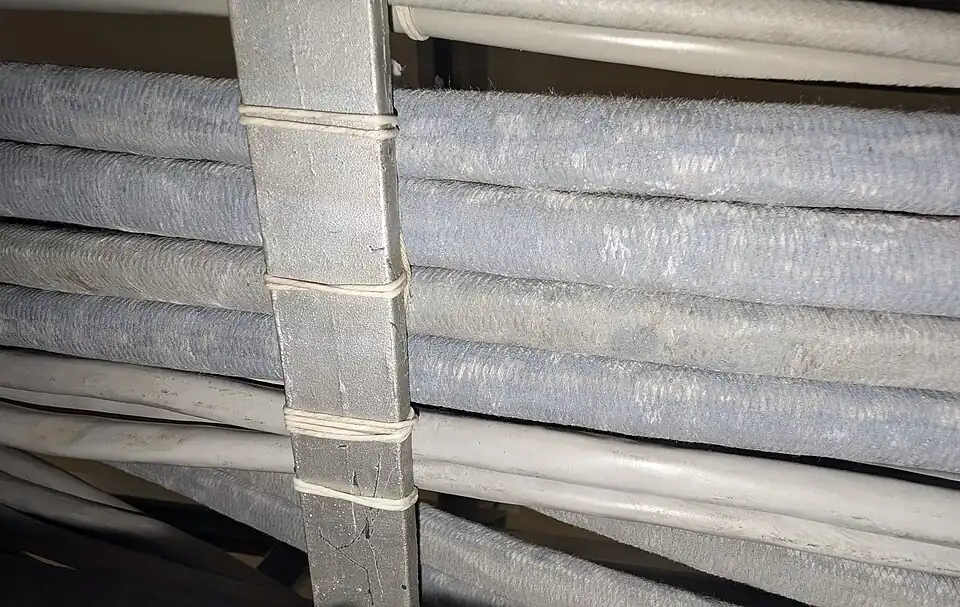 Back view of a bundle of cables secured to a frame with a Kansas City stitch. The bundle is stitched to the support in multiple places.